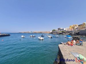 Barcos frente a Puerto pesquero de Los Abrigos y grupo de bañistas en Granadilla de Abona